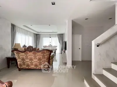 Elegant living room with classic sofa and modern decor, featuring large windows and neutral tones.