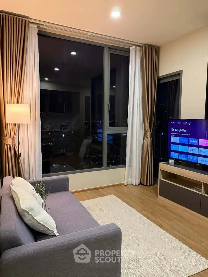 Modern living room with city view, cozy sofa, and smart TV setup.