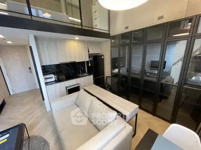 Modern loft apartment with sleek kitchen and cozy living area, featuring glass partitions and stylish furnishings.