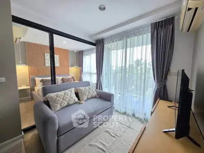 Modern living room with cozy sofa, large windows, and stylish decor in a contemporary apartment.