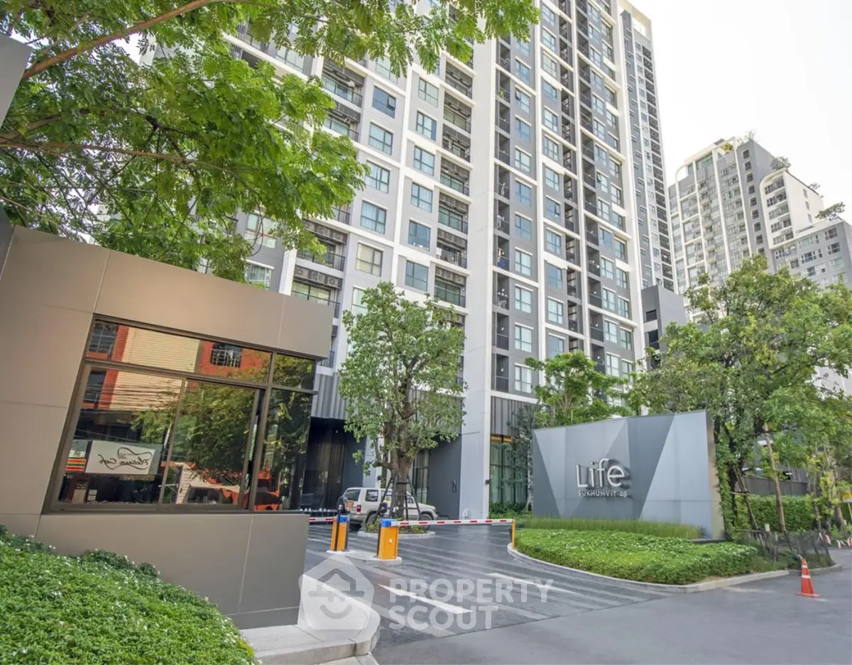 Modern high-rise residential building with lush greenery and secure entrance.