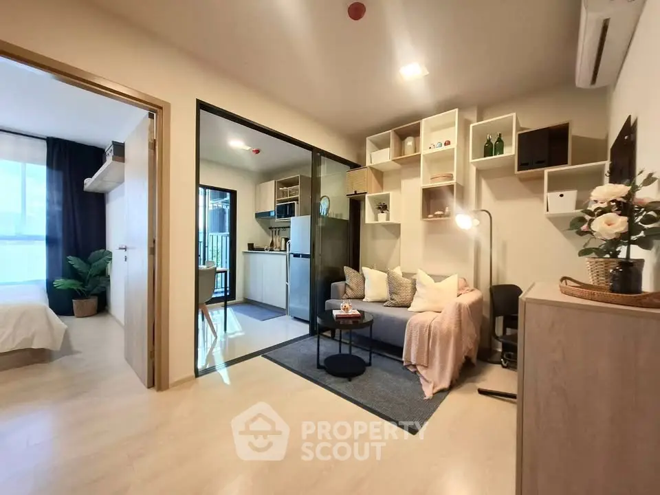 Modern open-plan living room with cozy decor and adjacent kitchen area