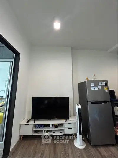 Modern living room with sleek TV setup and stainless steel fridge, perfect for urban living.