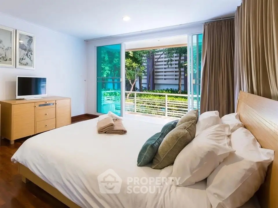 Spacious bedroom with modern decor and garden view balcony access.