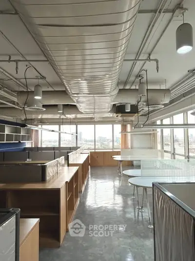 Spacious modern office space with large windows and industrial ceiling design