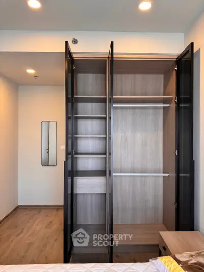 Spacious modern bedroom with open wardrobe and sleek wooden flooring