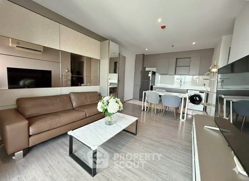 Modern living room with open kitchen, featuring sleek furniture and stylish decor.