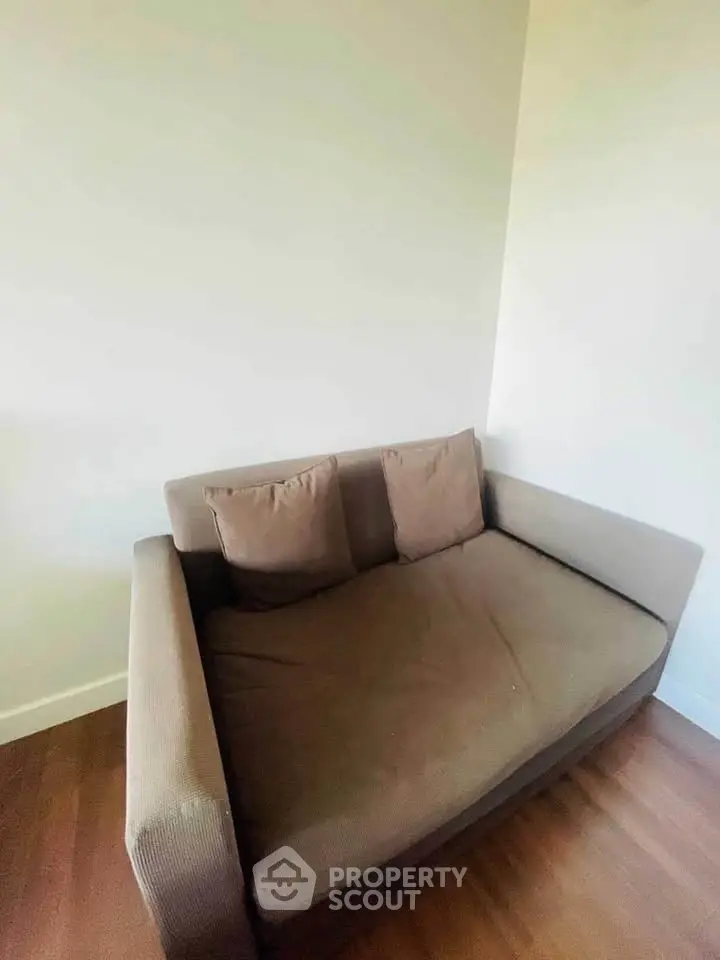 Cozy small sofa in a minimalist living room corner with wooden flooring.