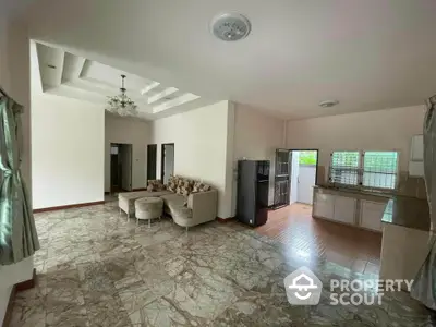 Spacious open-layout living room with elegant marble flooring and modern kitchen area.