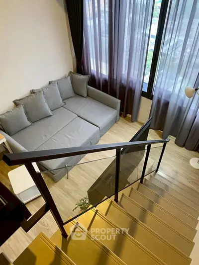 Modern living room with stylish gray sofa and large windows offering natural light.