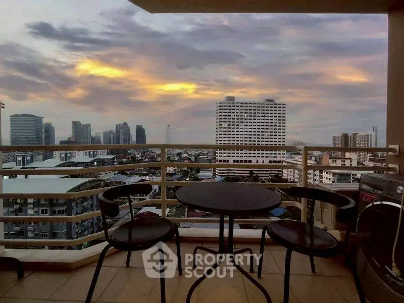 Stunning balcony view of city skyline at sunset with cozy seating area.