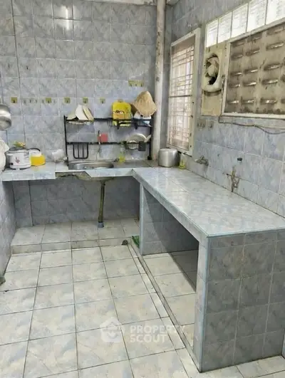 Spacious kitchen with tiled countertops and ample natural light, perfect for culinary enthusiasts.