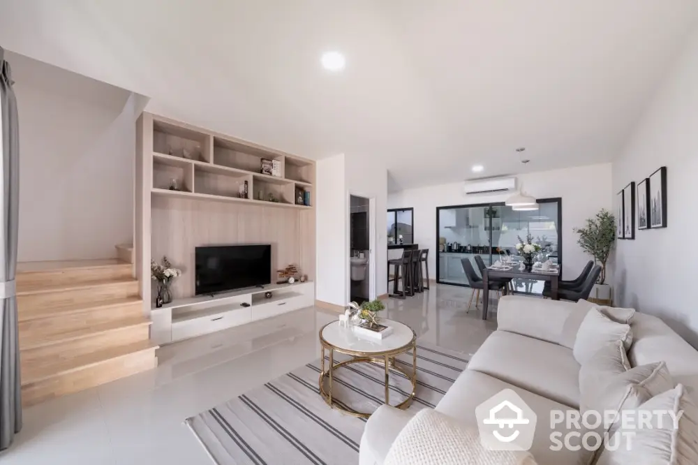 Spacious modern living room seamlessly connects to an outdoor balcony, featuring elegant furnishings and a chic neutral color palette.