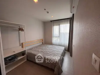 Cozy bedroom with natural light and modern furnishings in a high-rise apartment.