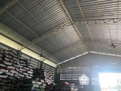 Spacious warehouse interior with high metal roof and stacked goods