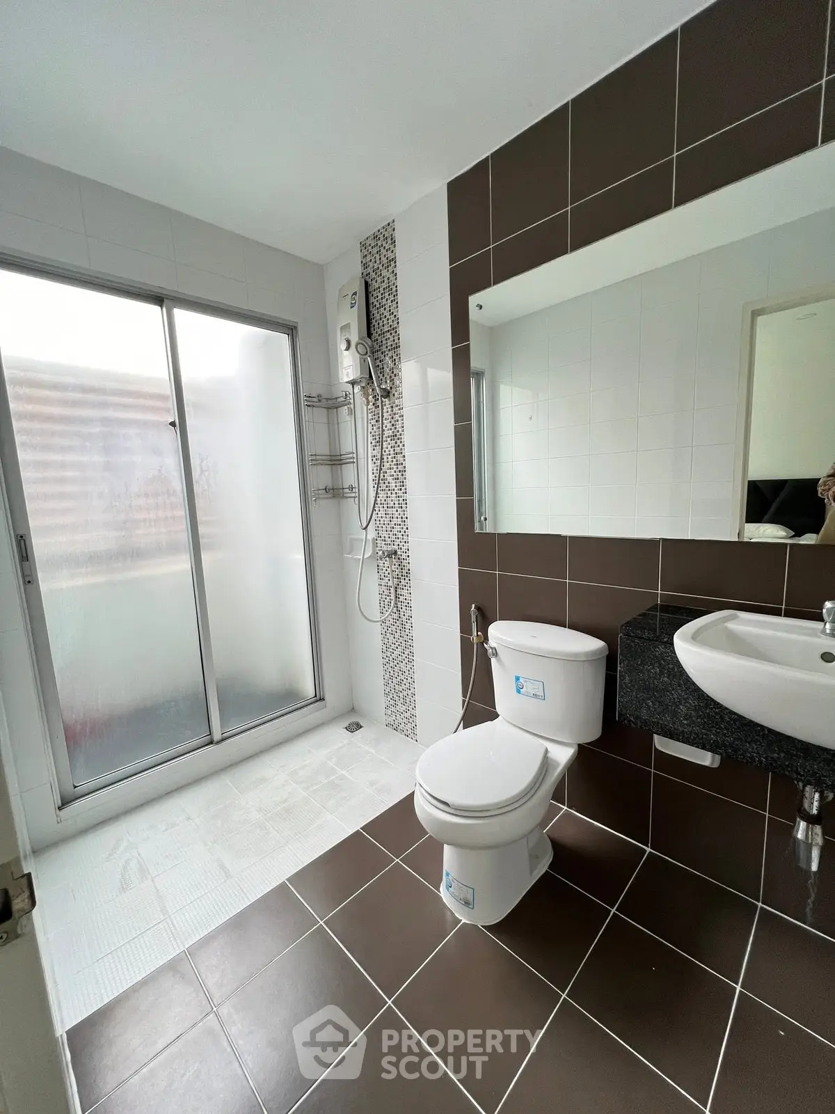 Modern bathroom with sleek design, featuring a glass shower enclosure and stylish brown and white tiles.