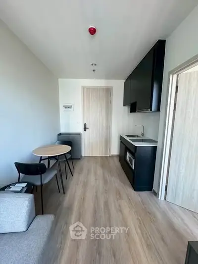 Modern compact studio apartment with kitchenette and dining area.