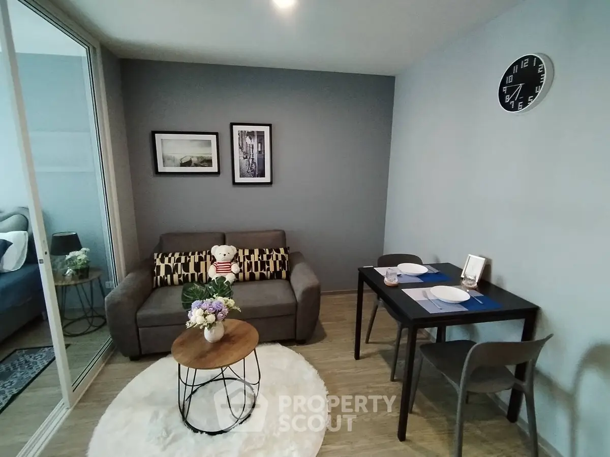 Cozy living room with modern decor, featuring a plush sofa, stylish coffee table, and intimate dining area.