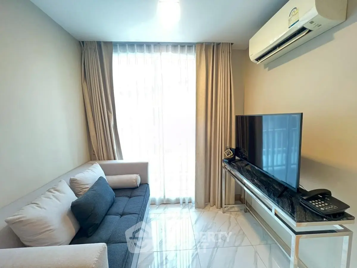 Modern living room with sleek furniture and natural light, featuring a stylish sofa and flat-screen TV.