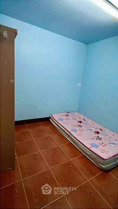 Cozy minimalist bedroom with single mattress and tiled flooring, perfect for compact living.