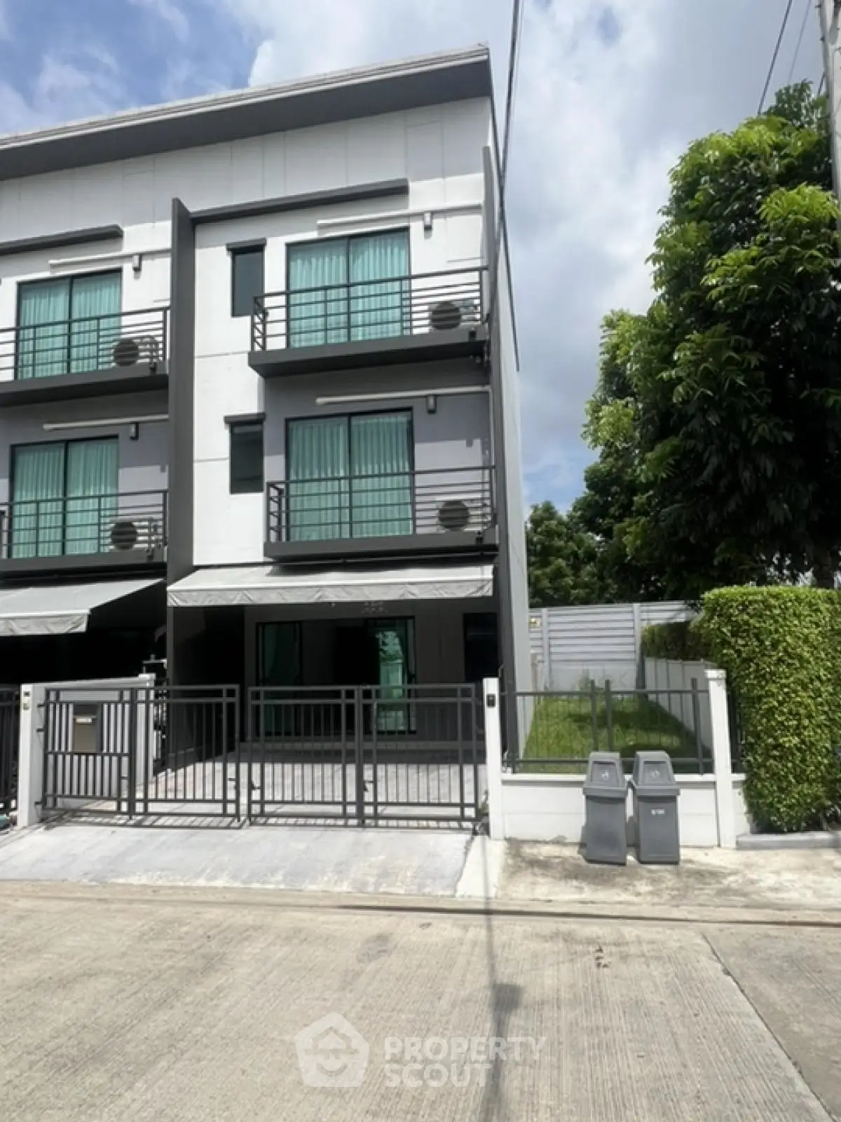 Modern three-story townhouse with sleek design and gated entrance in a serene neighborhood.