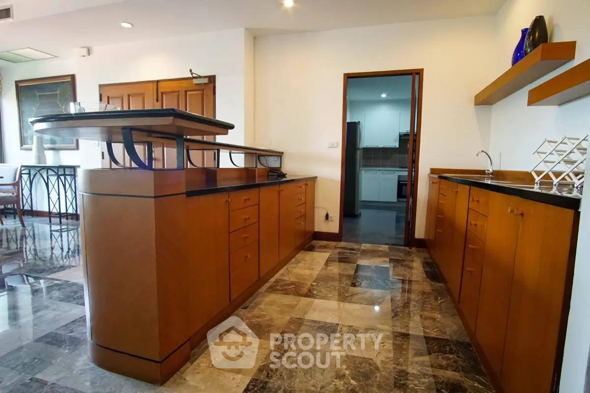 Spacious kitchen with elegant wooden cabinetry and marble flooring in a modern home.