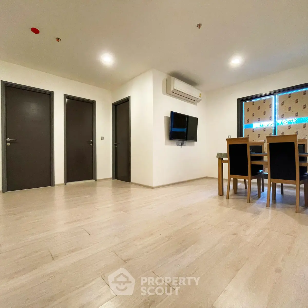 Spacious modern living room with dining area and wall-mounted TV, featuring sleek wooden flooring and ambient lighting.