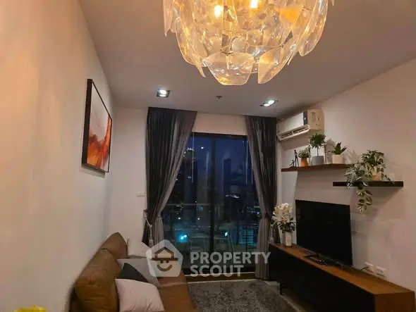 Stylish living room with modern chandelier and city view balcony, perfect for urban living.