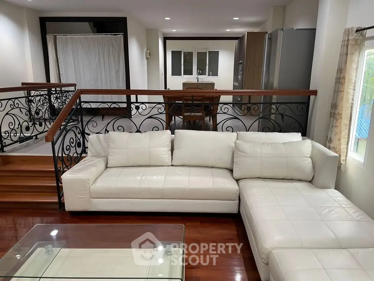 Spacious living room with elegant white sofa and modern open kitchen layout