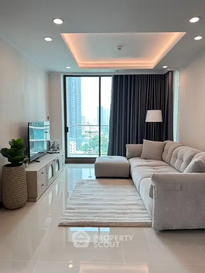 Modern living room with large sofa, TV, and city view from balcony in high-rise apartment.