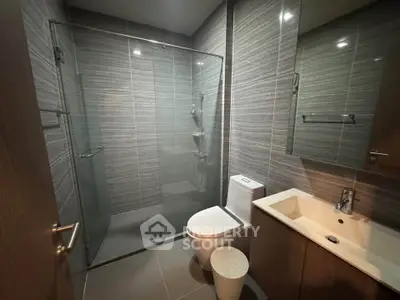 Modern bathroom with glass shower and sleek fixtures in contemporary apartment.