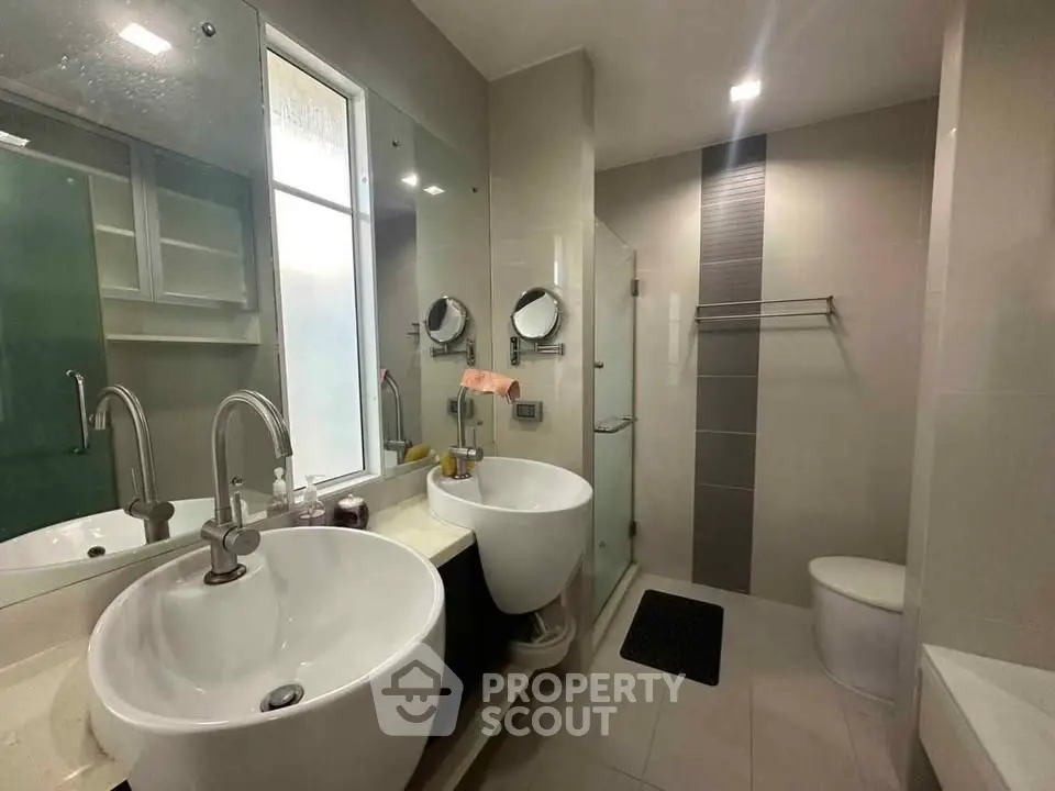 Modern bathroom with dual sinks and glass shower enclosure