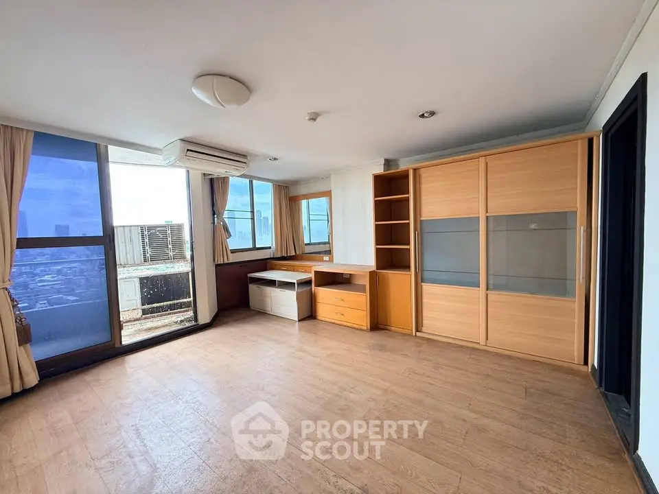Spacious living room with large windows and wooden flooring offering stunning city views.