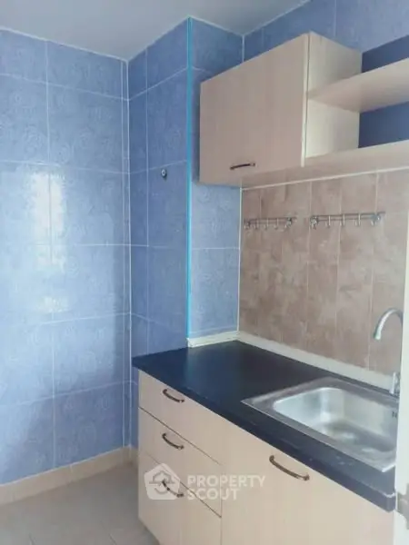 Compact kitchen with blue tile walls and modern cabinetry