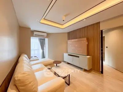 Modern living room with sleek design, featuring a large TV and comfortable seating.