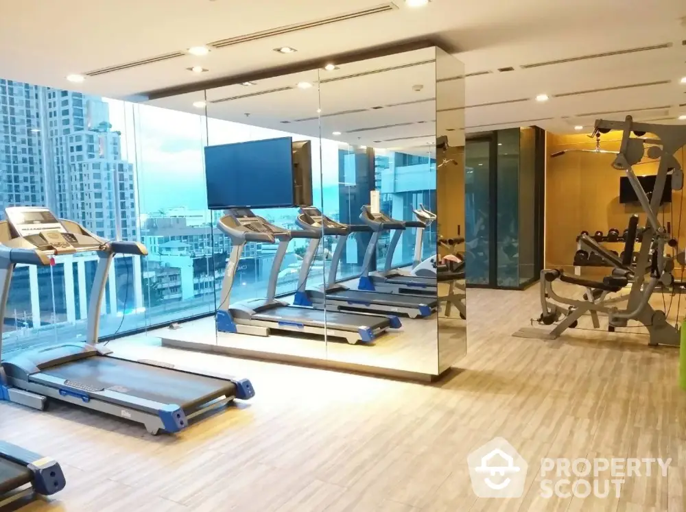 Modern gym with city view featuring treadmills and fitness equipment