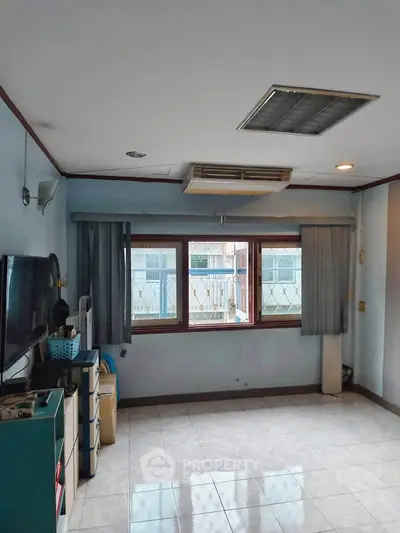 Spacious living room with large windows and air conditioning, perfect for comfortable living.