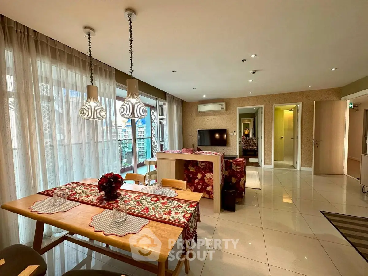 Spacious living room with modern decor and large windows offering city views.