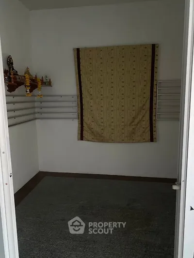Cozy small room with wall-mounted shelves and a decorative curtain, ideal for storage or a compact study area.