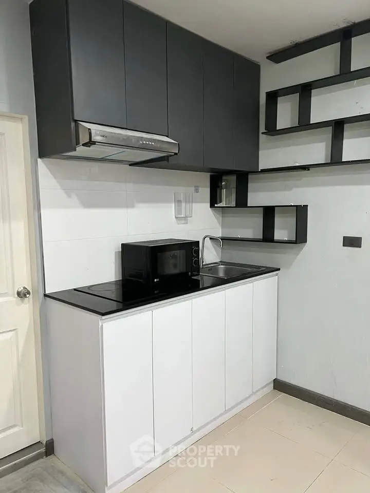 Modern kitchen with sleek black cabinets and built-in microwave