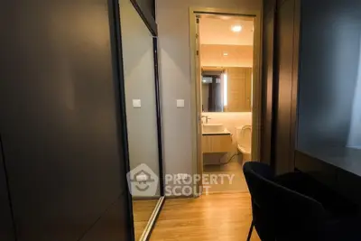 Modern apartment hallway leading to a stylish bathroom with sleek fixtures.