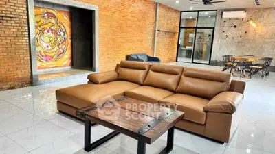 Spacious modern living room with leather sofa and artistic brick wall design.