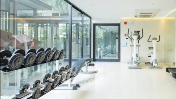 Modern gym with glass walls and fitness equipment in luxury residential building.