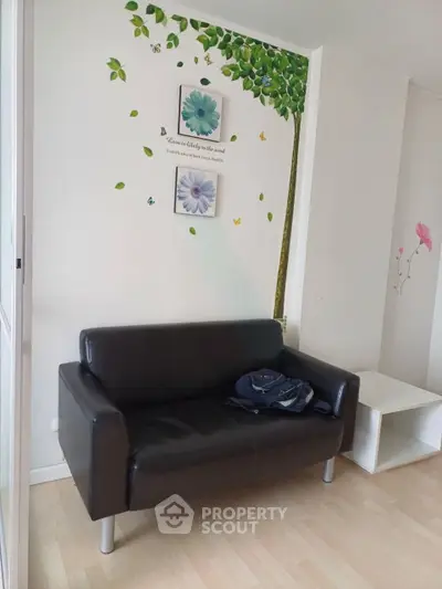 Charming living room with stylish black sofa and artistic wall decor, perfect for cozy relaxation.