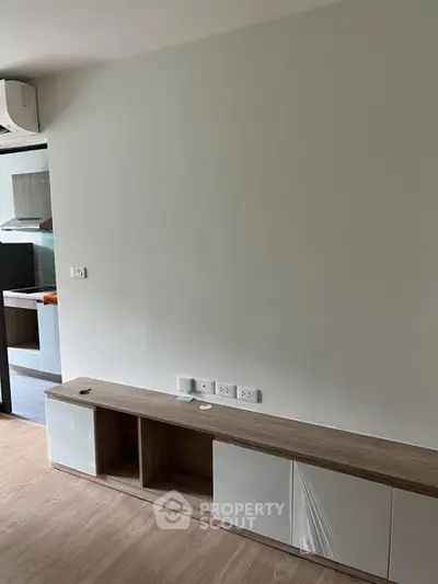 Modern minimalist living room with built-in storage and open kitchen view.