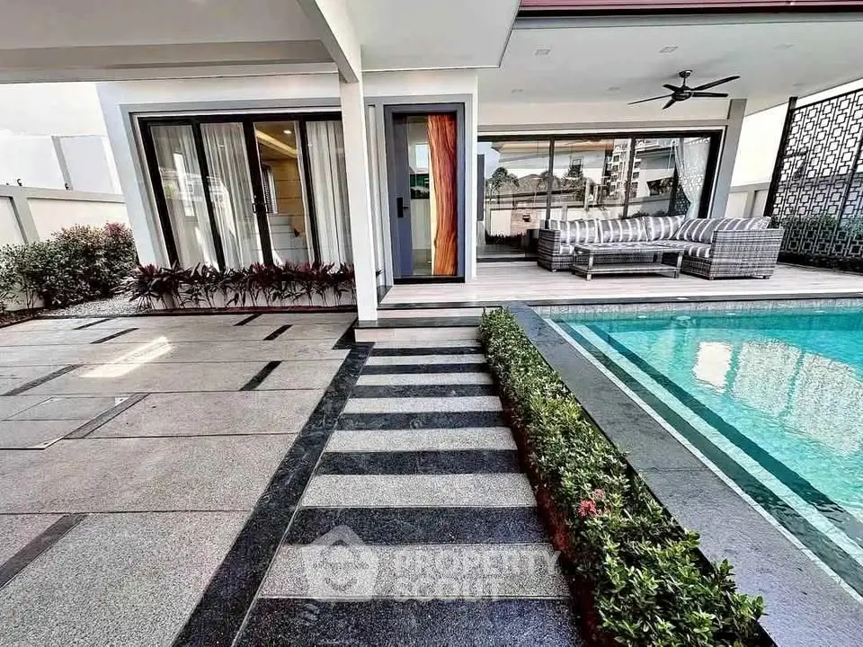 Luxurious modern home with poolside patio and stylish outdoor seating area.