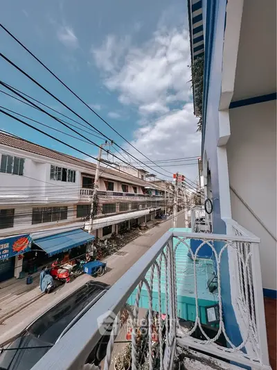 Charming urban balcony view with vibrant street life and clear blue skies.