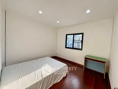 Spacious bedroom with wooden flooring and natural light