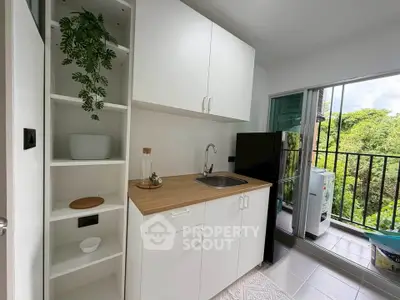 Modern kitchen with open layout and balcony view, featuring sleek cabinetry and appliances.
