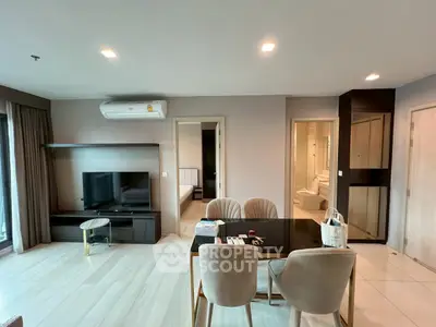 Modern open-plan living room with dining area and view into bedroom and bathroom.